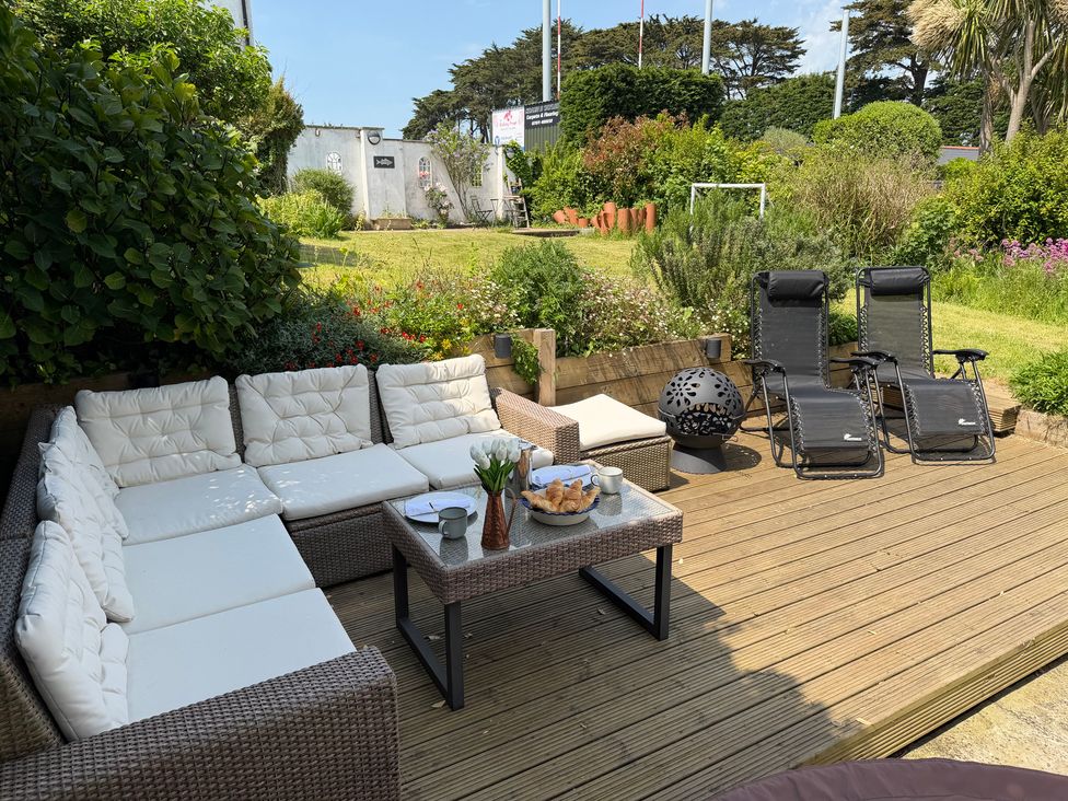 A garden with outdoor seating and lounge chairs at Lorrell in Salcombe
