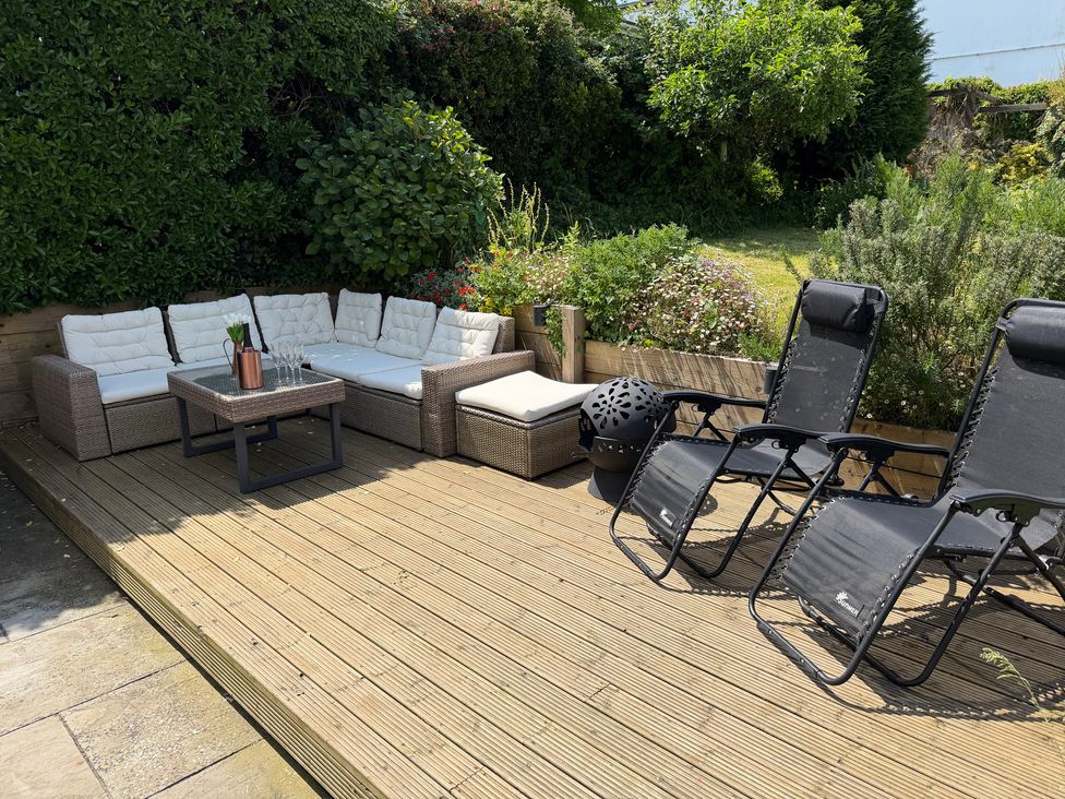 An outdoor seating area with a sofa and chairs at Lorrell in Salcombe