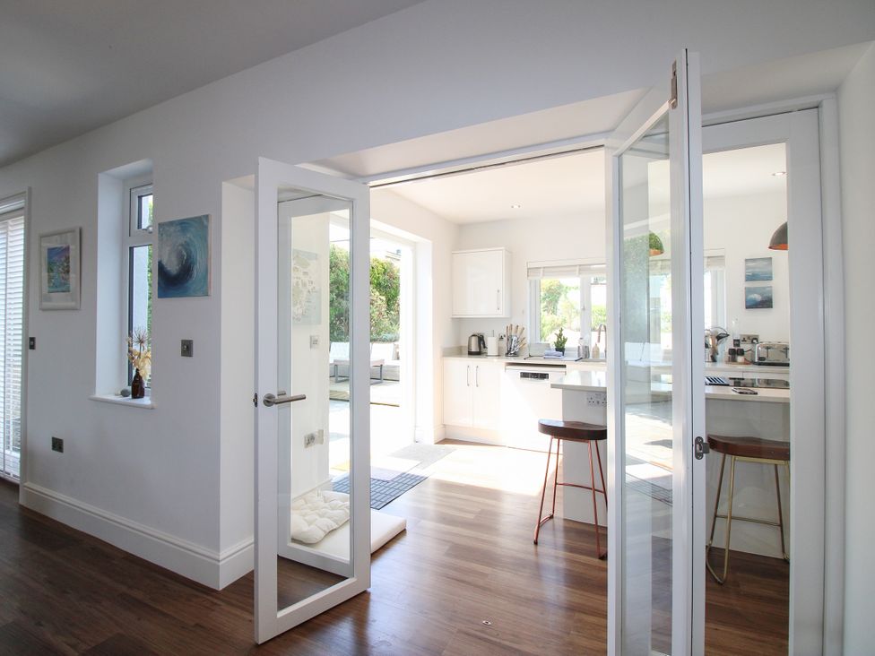 A kitchen with open doors and view of outdoor area at Lorrell in Salcombe