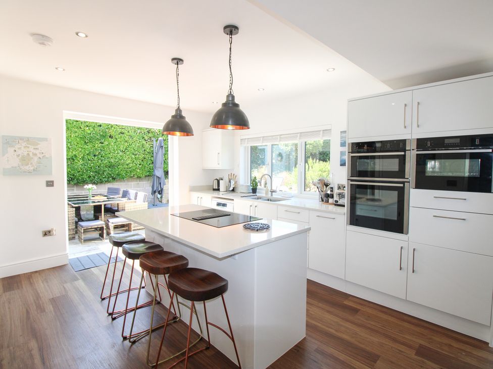 A kitchen with an island and bar stools at Lorrell in Salcombe