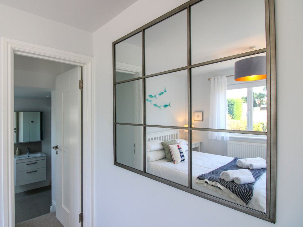 A bedroom with a bed and window viewed through a mirror at Lorrell in Salcombe