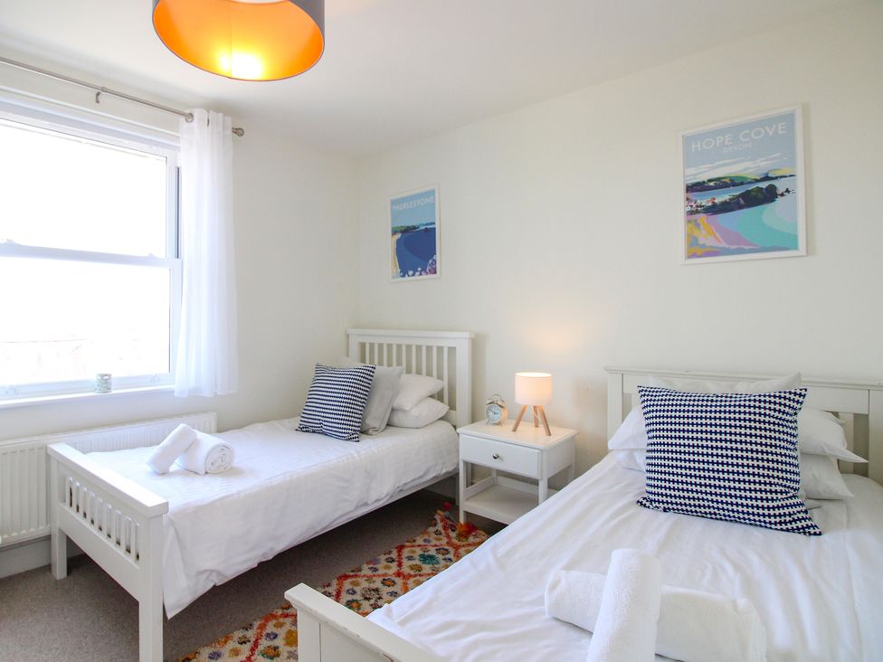 A bedroom with two beds and a bedside table at Lorrell in Salcombe