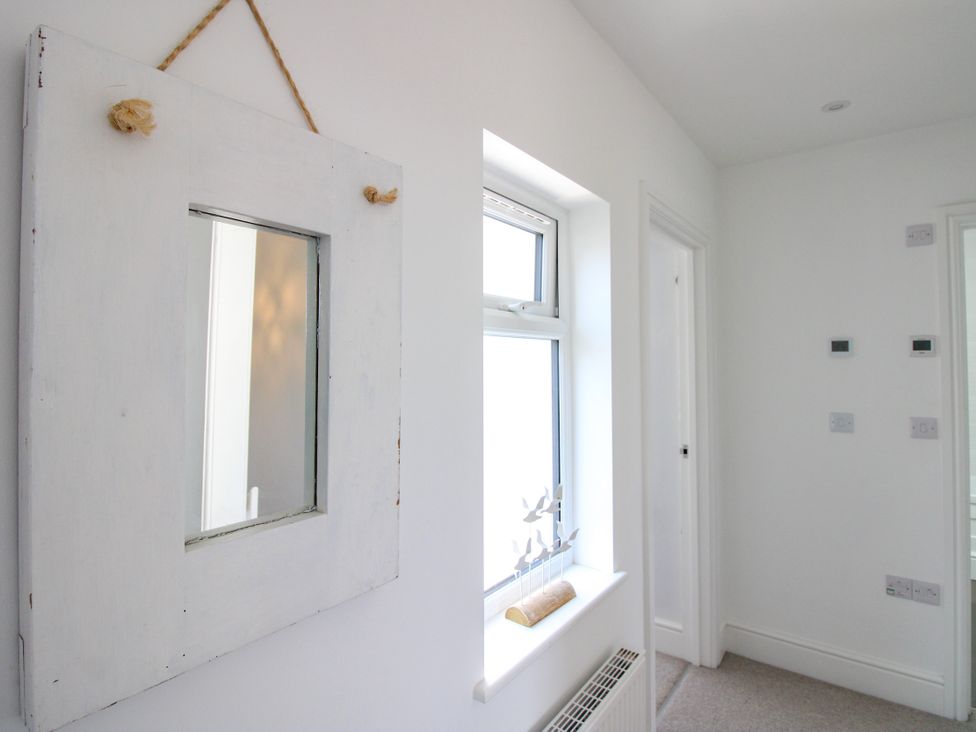 A hallway with a mirror and window at Lorrell in Salcombe