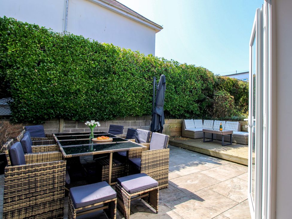 A garden with a dining table and seating area at Lorrell Salcombe
