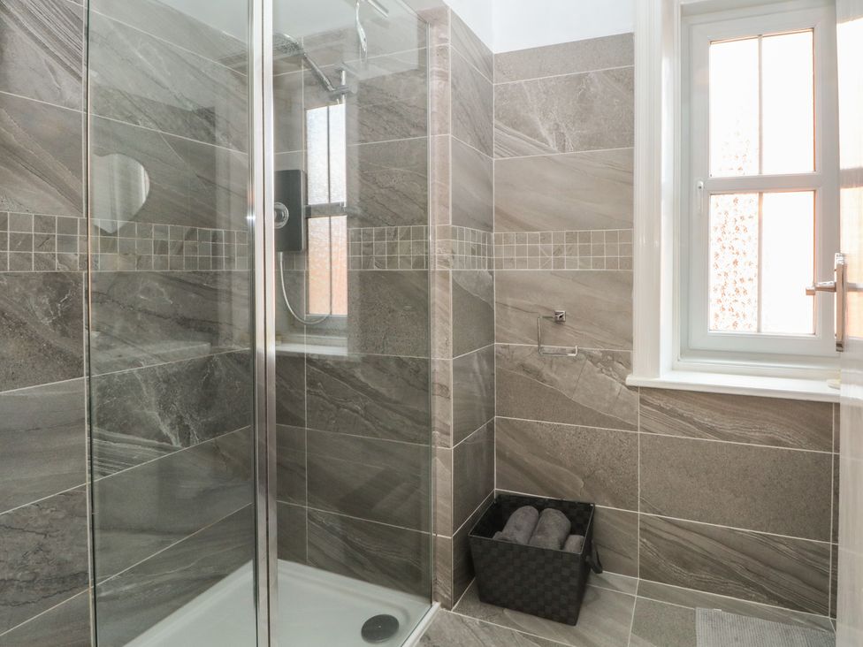 A shower with glass enclosure and towels in a basket at Apartment 2 in Lytham St. Annes