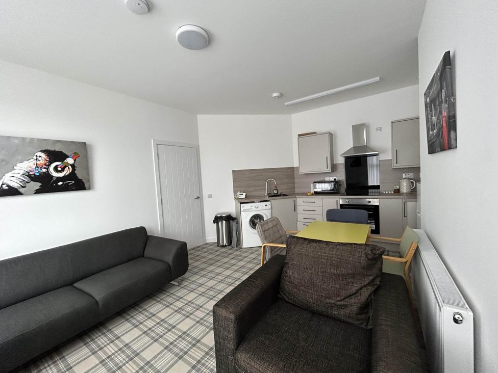 A living room with a sofa, armchair, and kitchen area at Buckie Haven 3 Bed Contractors Business Travellers in Buckie