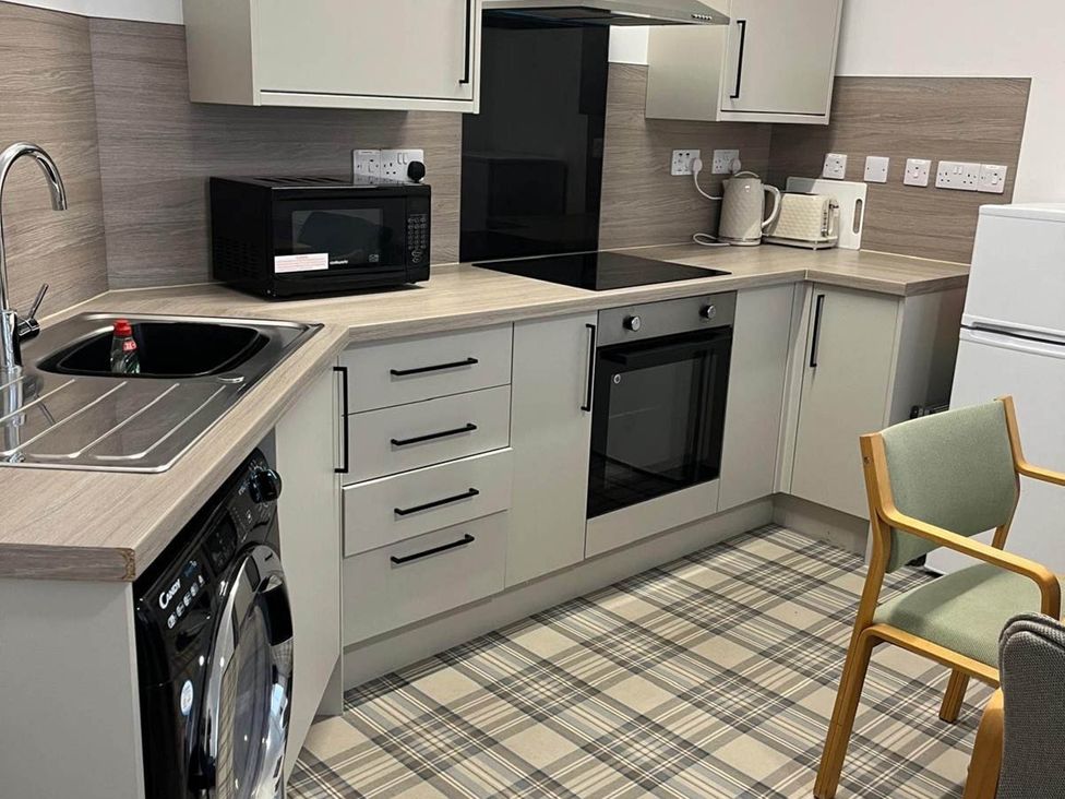 A kitchen with countertops, sink, microwave, and washing machine at Buckie Haven 3 Bed Contractors Business Travellers in Buckie