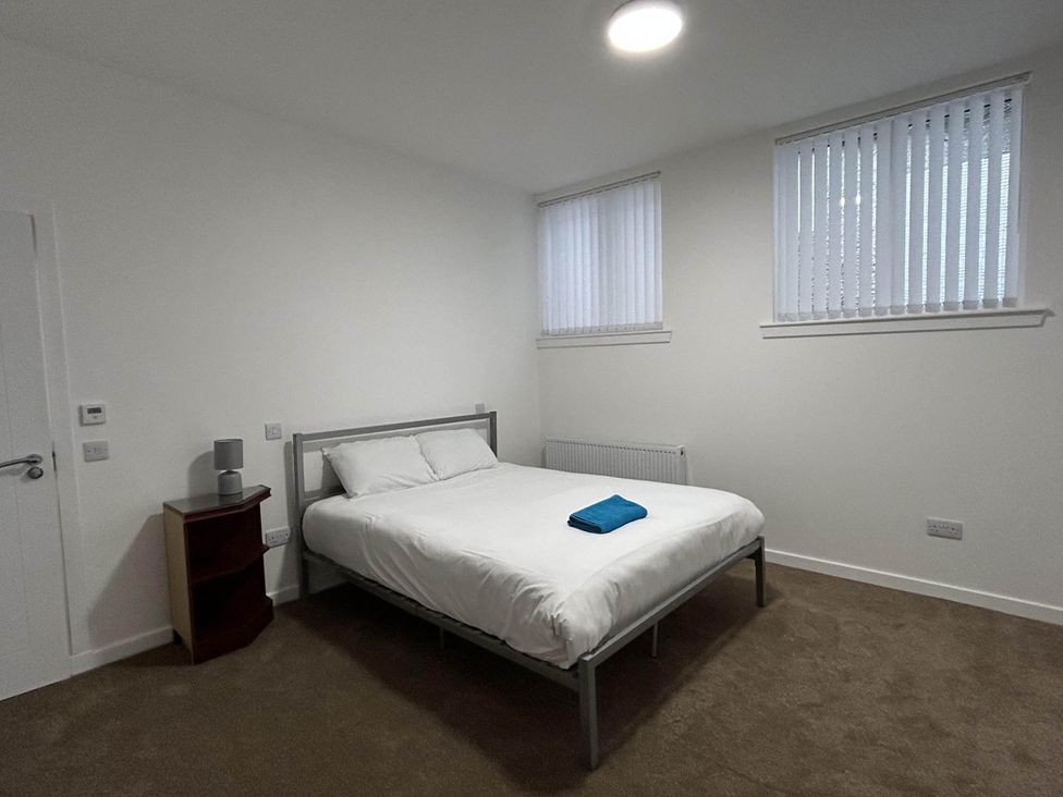 A bedroom with a bed, towel, and windows at Buckie Haven 3 Bed Contractors Business Travellers in Buckie
