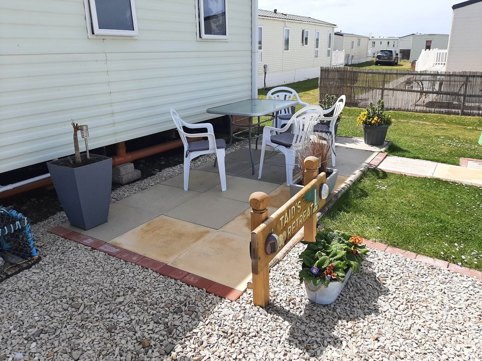 An outdoor seating area with a table and chairs at Taid's Retreat Silversands Cove beach lossiemouth