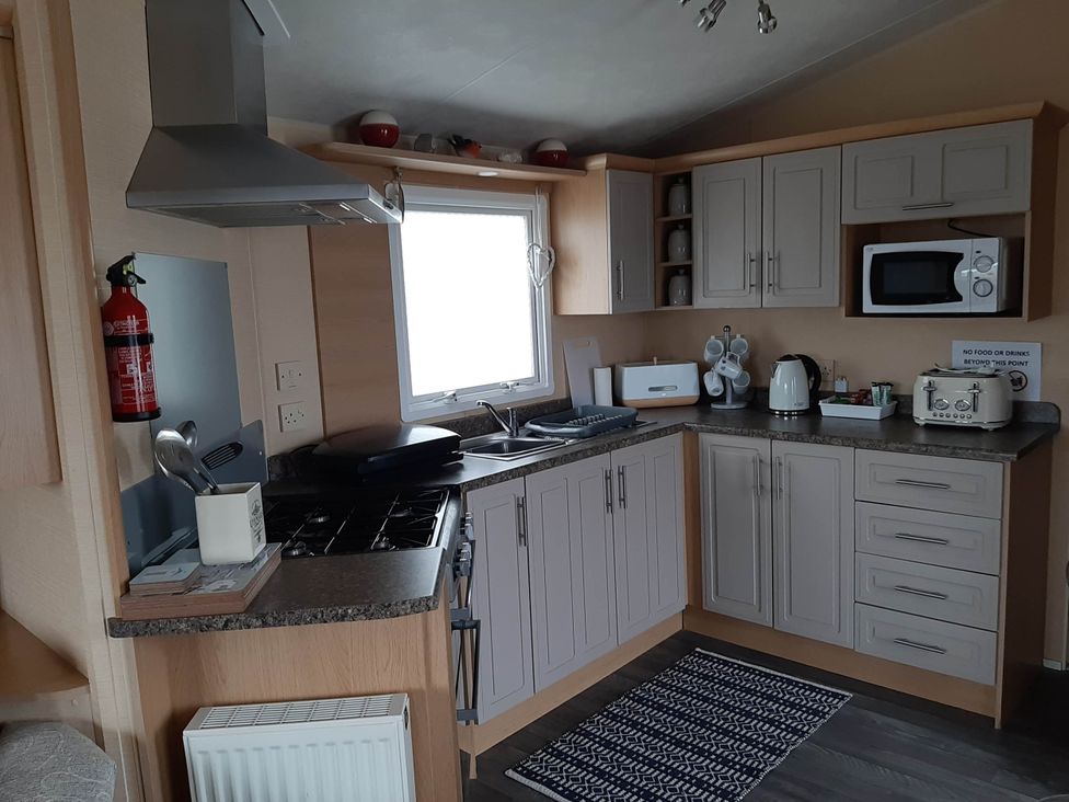 A kitchen with appliances and storage at Taid's Retreat Silversands Cove beach lossiemouth