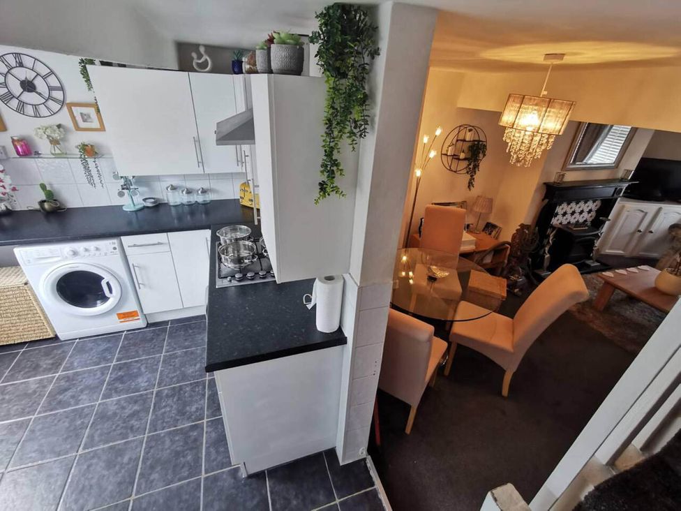 A kitchen with a washing machine and stove adjoining a dining area at Stunning 2-Bed House in Macclesfield Cheshire