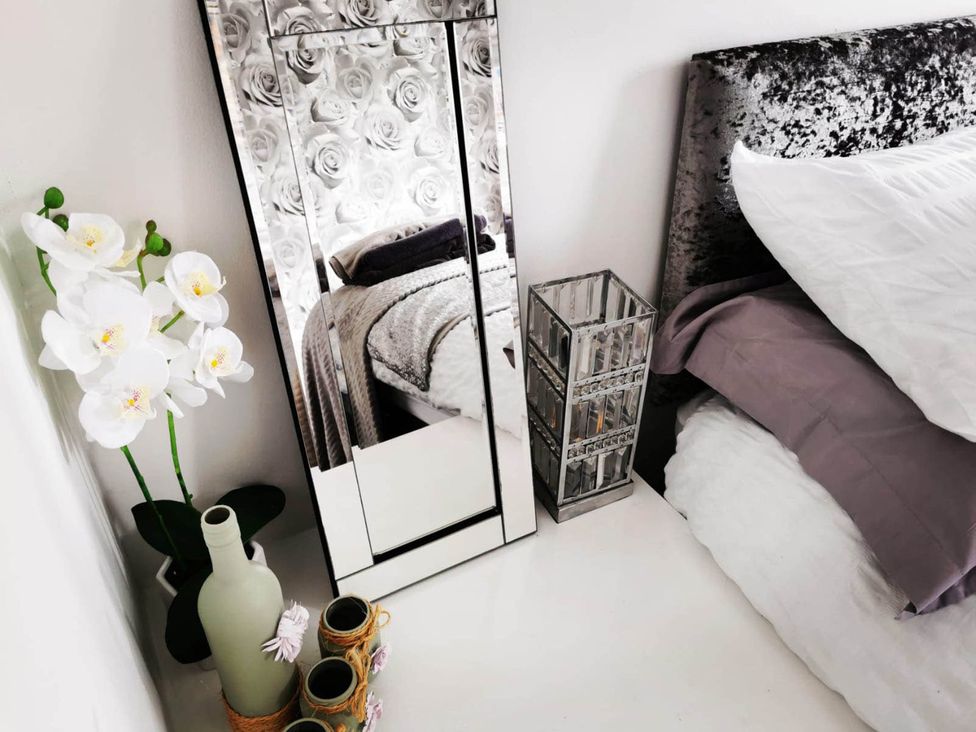 A bedroom featuring a mirror, a bed with pillows and a throw blanket at Stunning 2-Bed House in Macclesfield Cheshire