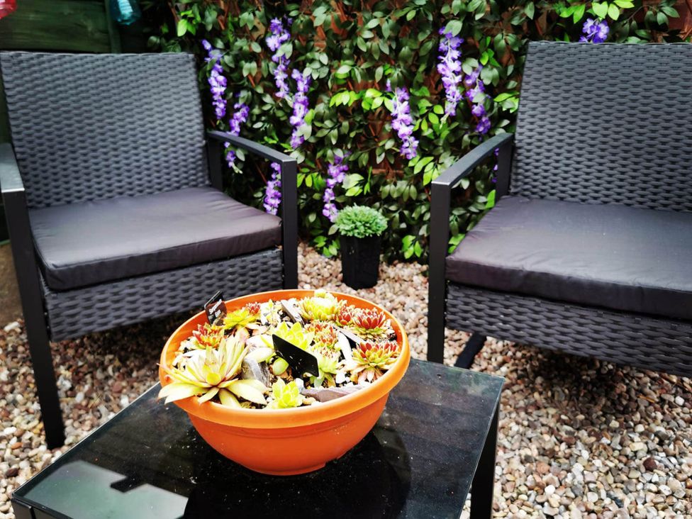A garden setting with two chairs and a succulent plant arrangement in a bowl at Stunning 2-Bed House in Macclesfield Cheshire