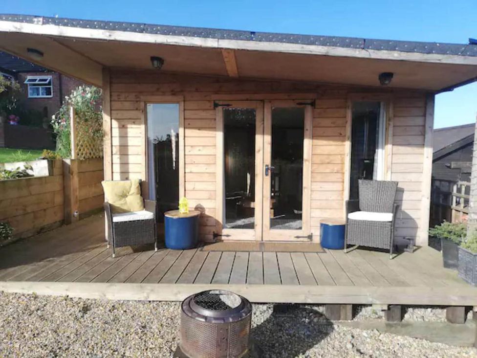 A wooden cabin with double doors and outdoor chairs at Peaceful Cabin in Skegby -Sleeps2- Fire Pit Stanton Hill