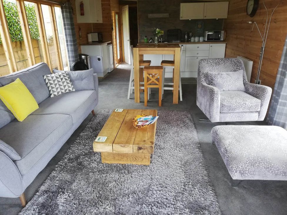 A living room with a sofa, coffee table, and kitchen area at Peaceful Cabin in Skegby -Sleeps2- Fire Pit Stanton Hill