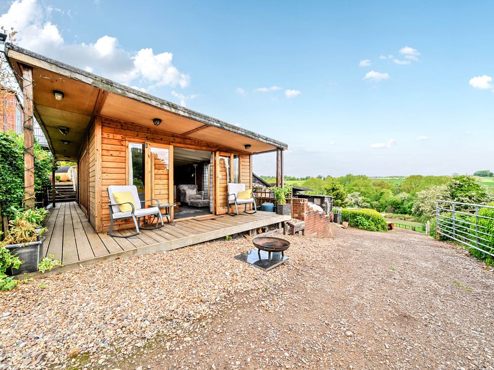 An outdoor area with a wooden cabin and chairs at Peaceful Cabin in Skegby -Sleeps2- Fire Pit, Stanton Hill