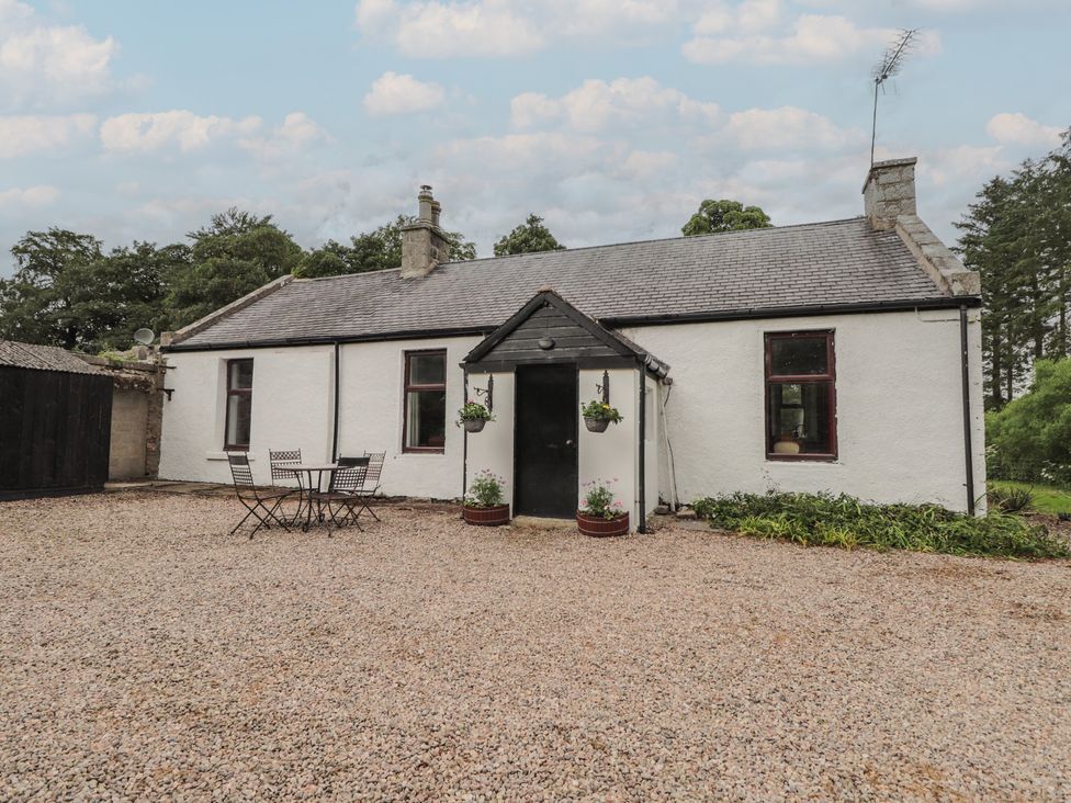 An outdoor view of a house with a table and chairs at Keepers Cottage in New Deer