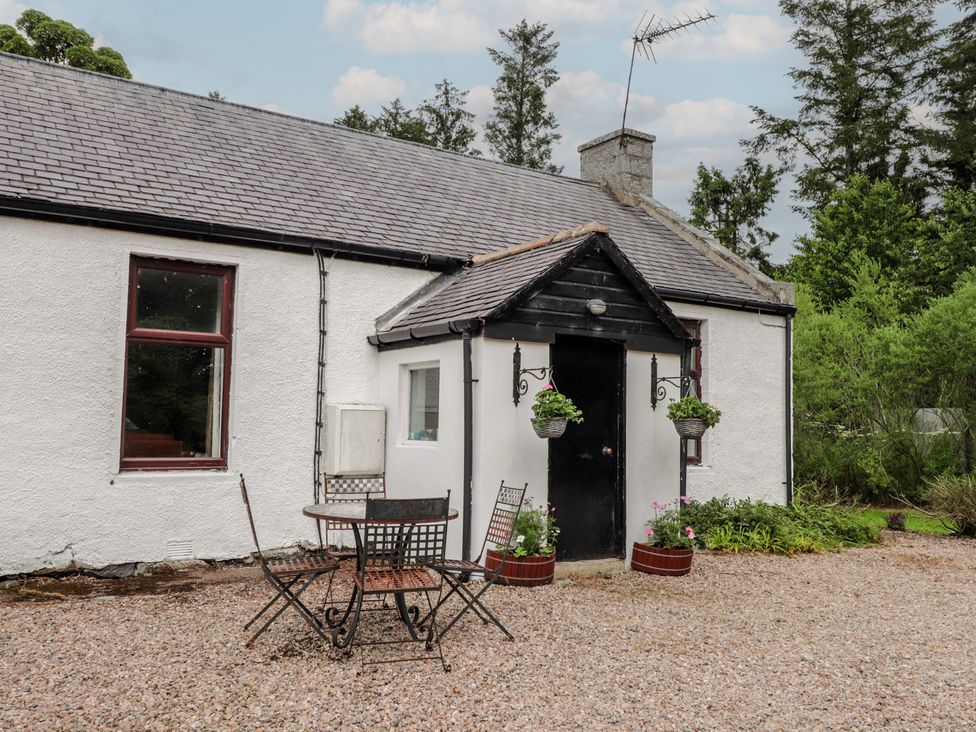 A cottage with a front door, table, and chairs at Keepers Cottage, New Deer