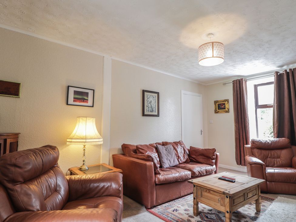 A living room with leather sofas and a wooden table at Keepers Cottage in New Deer