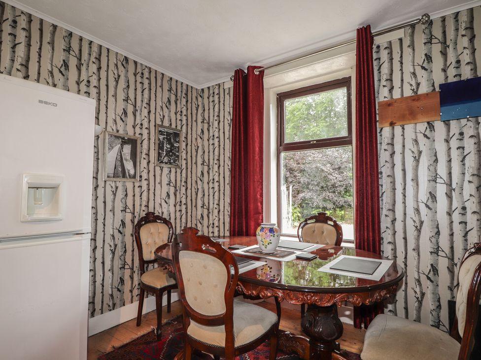 A dining room with a table, chairs and a refrigerator at Keepers Cottage in New Deer