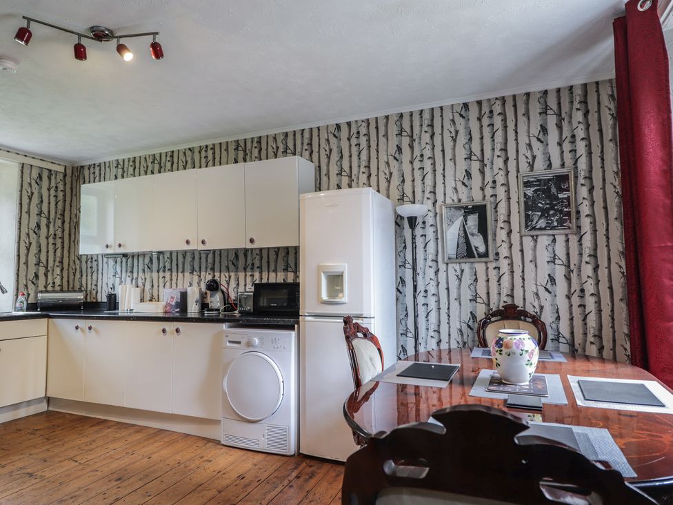 A kitchen with appliances and a dining table at Keepers Cottage in New Deer