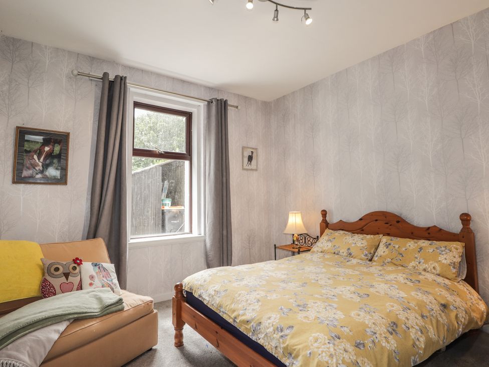 A bedroom with a bed and sofa at Keepers Cottage in New Deer