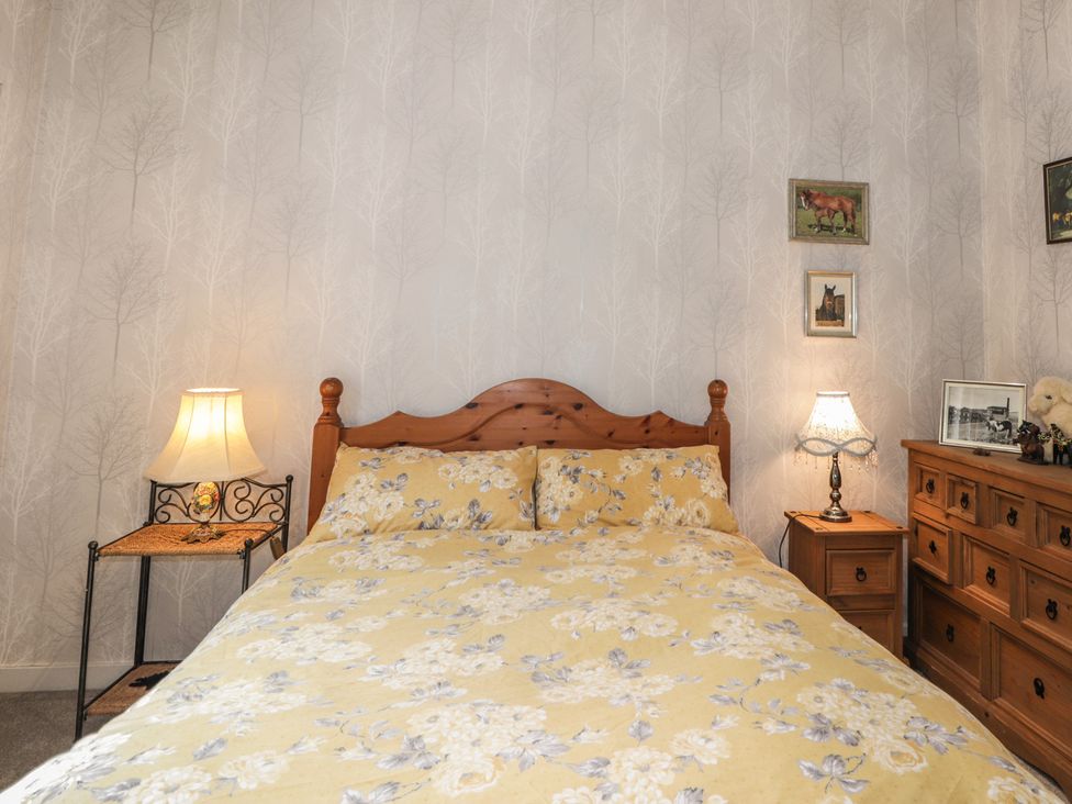A bed with floral bedding in a bedroom at Keepers Cottage New Deer