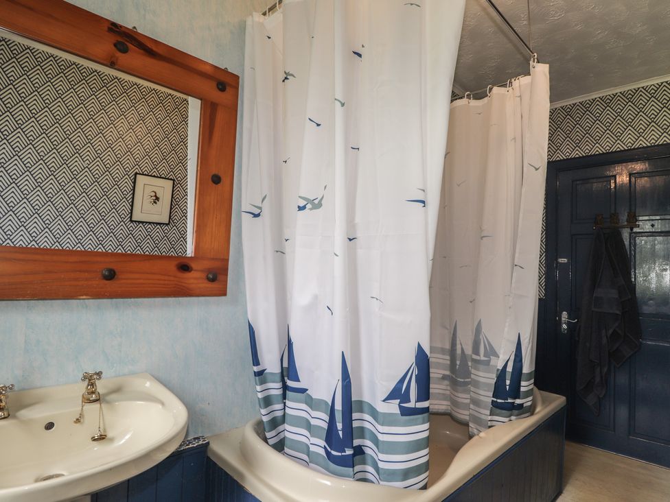A bathroom with a bathtub and sink at Keepers Cottage, New Deer