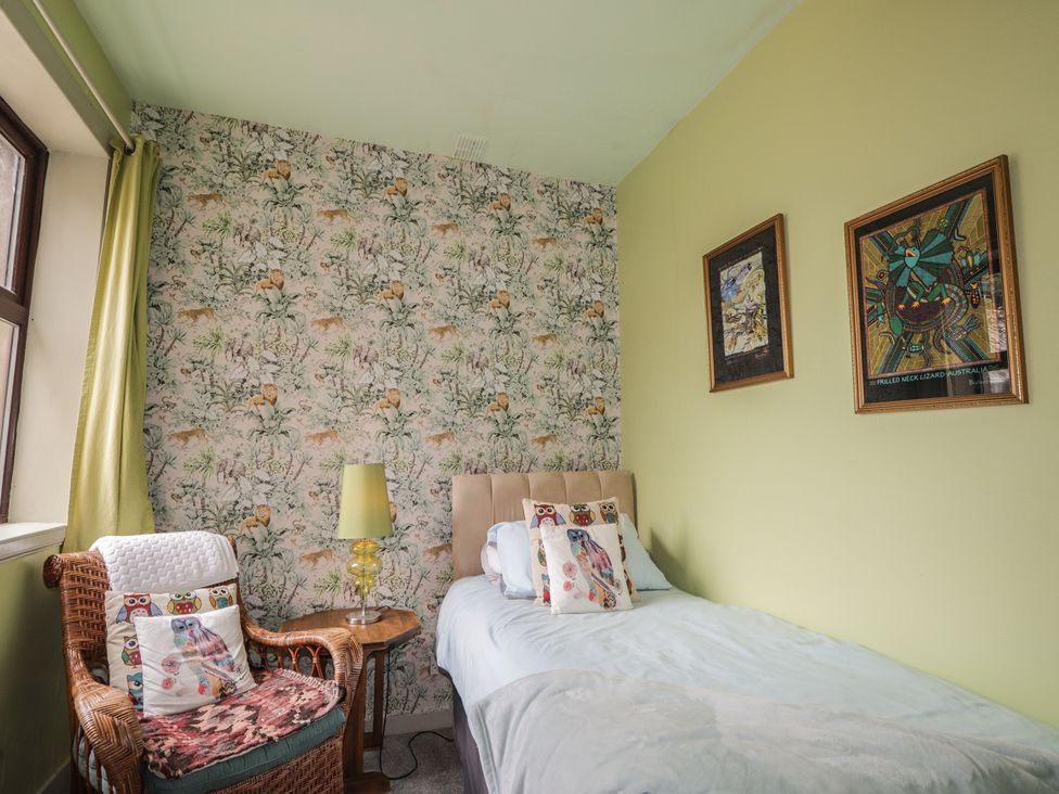 A bedroom with a bed and a chair at Keepers Cottage in New Deer