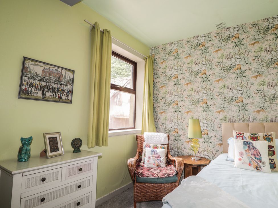 A bedroom with a bed and chair at Keepers Cottage in New Deer