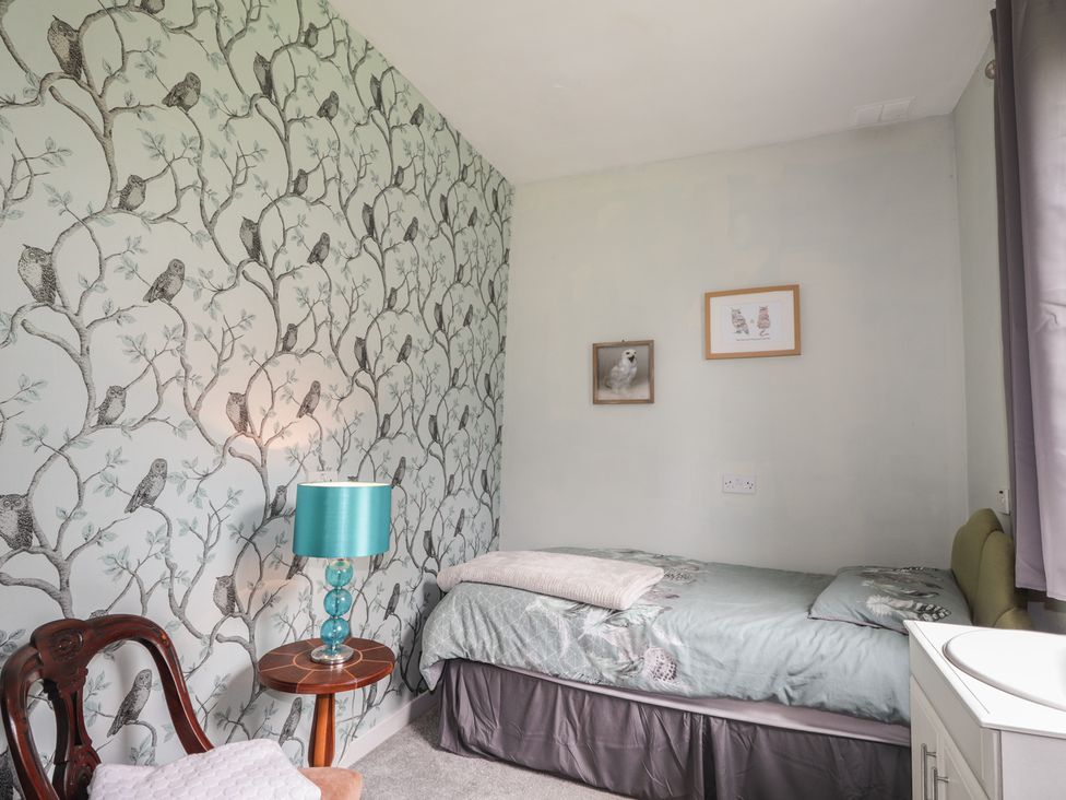 A bedroom with a bed, lamp, and wall art at Keepers Cottage in New Deer