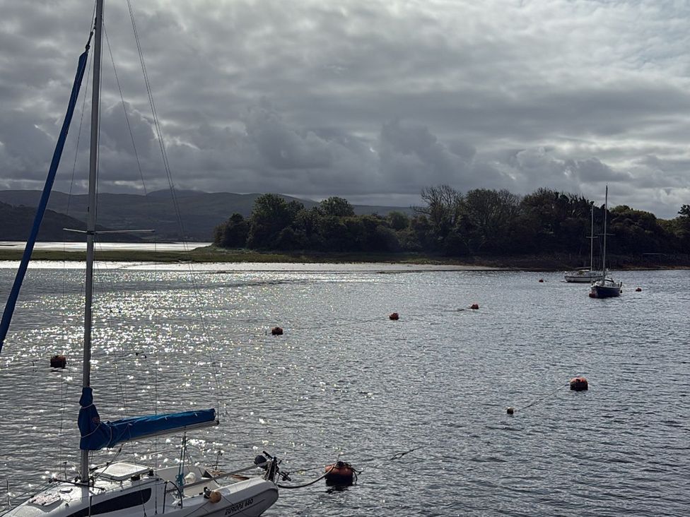 A sailboat on water with an island in the background at 10 Oakley Wharf Porthmadog