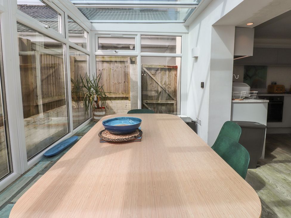 A conservatory with a table and chairs at Kiloran Rhosneigr
