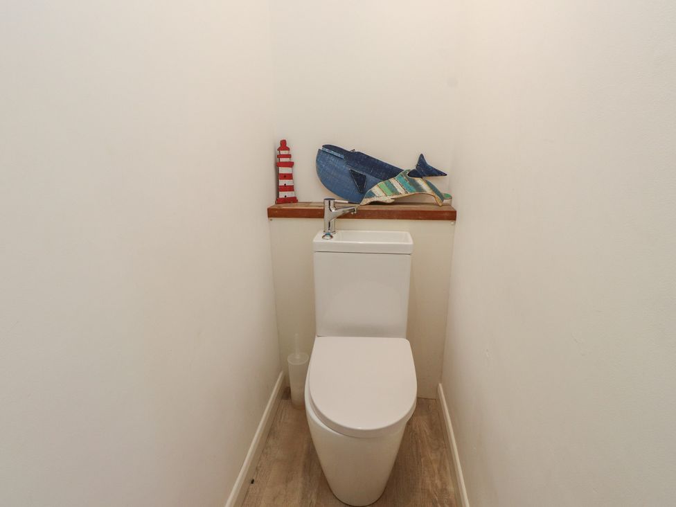 A bathroom with a toilet and decorative items at Kiloran in Rhosneigr