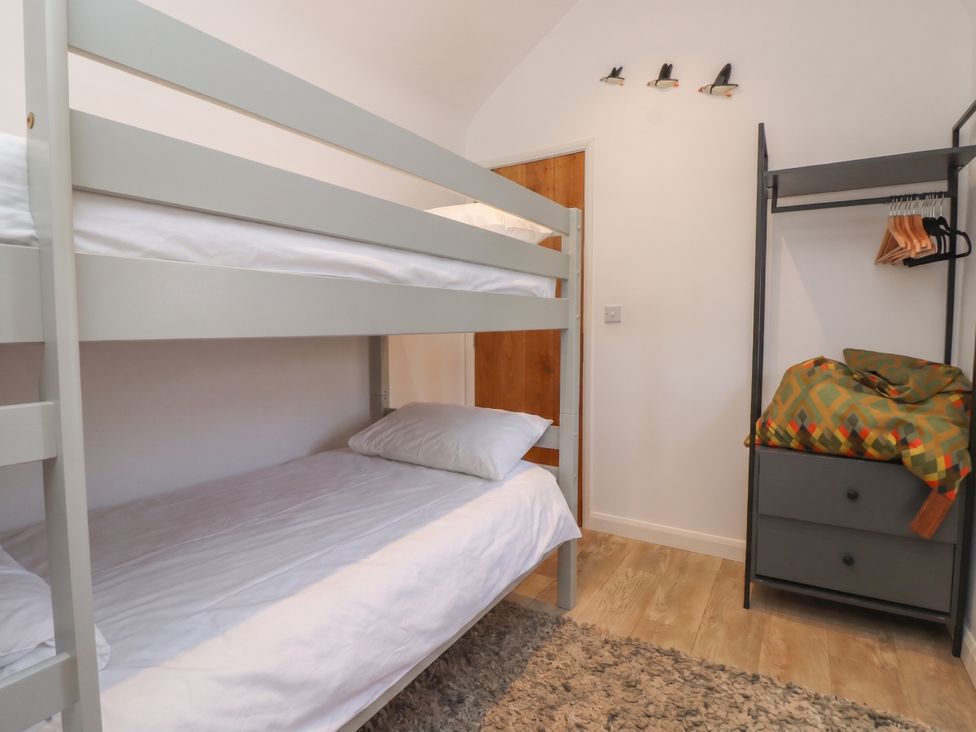 A bedroom with a bunk bed and wardrobe at Kiloran in Rhosneigr