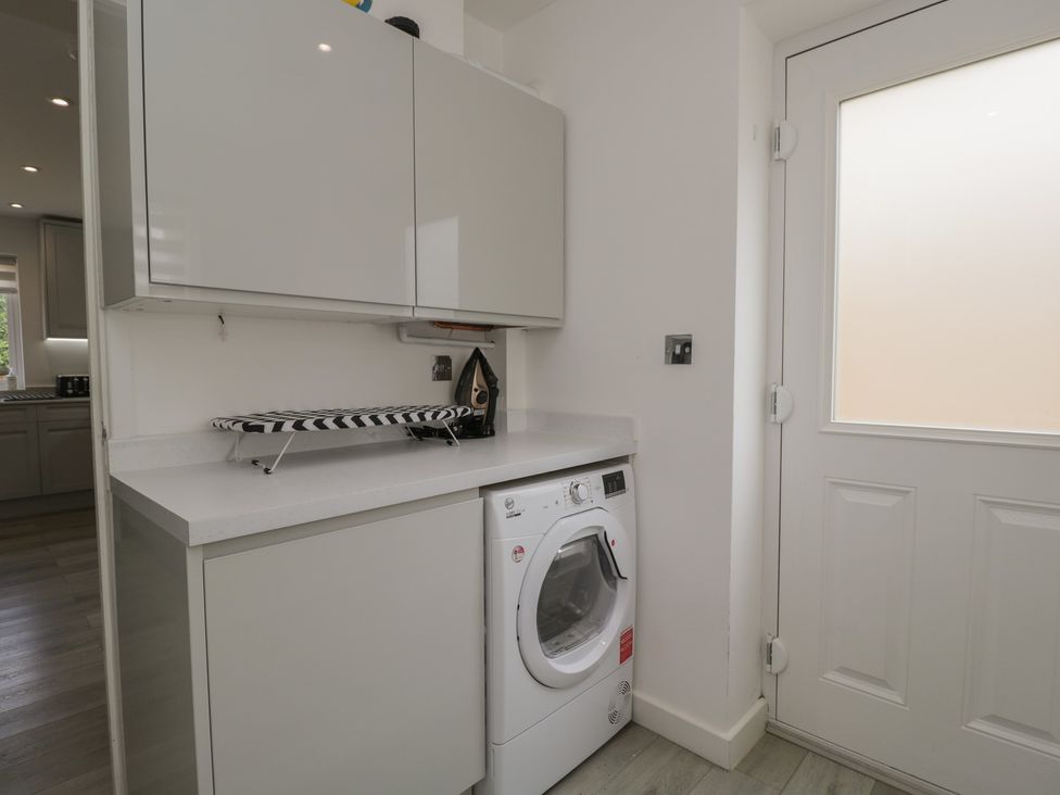 A laundry room with a washing machine and iron board at 1 Brunel Court