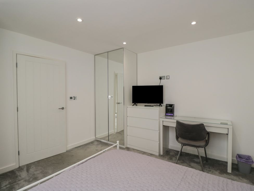 A bedroom with a bed, desk, television, and drawer at 1 Brunel Court