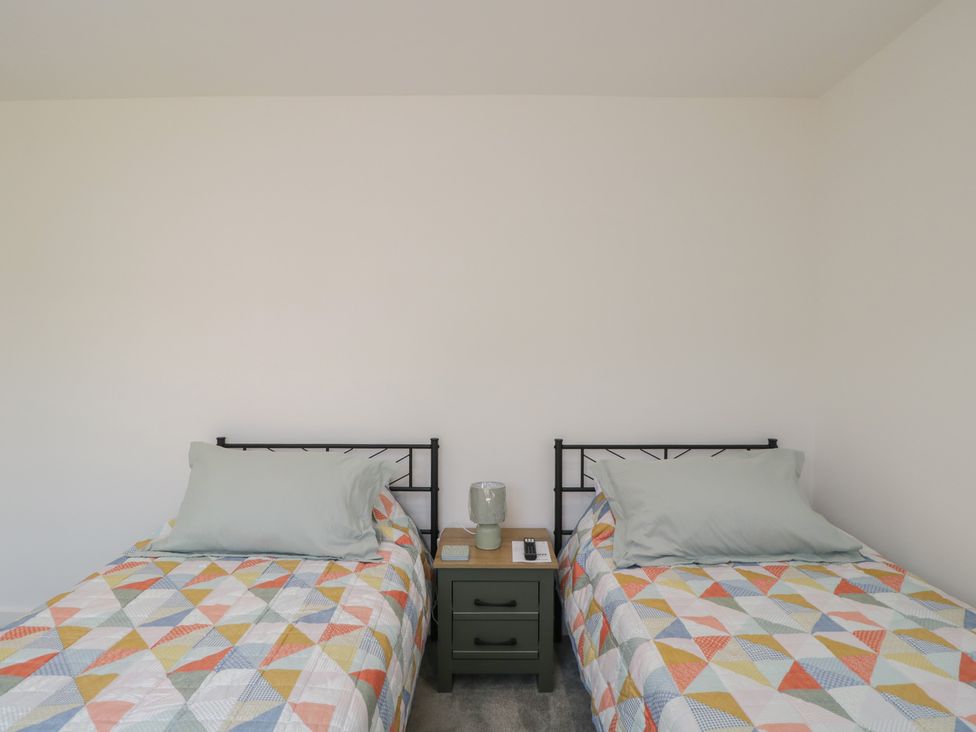 Two beds with quilts and a bedside table in a bedroom at 1 Brunel Court