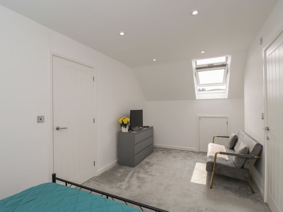 A bedroom with a bed, television, and an armchair at 1 Brunel Court
