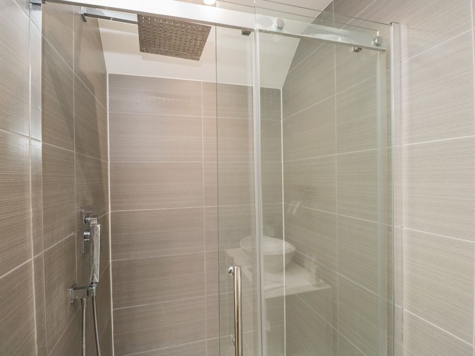 A shower with a glass door and wall tiles at 1 Brunel Court