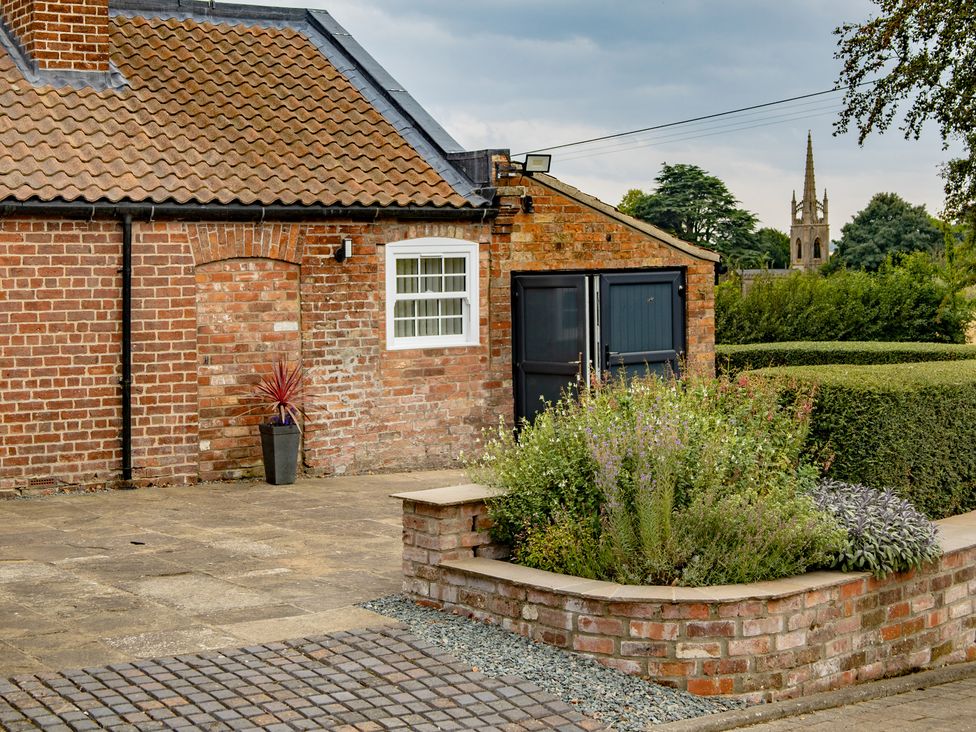 A garden with a brick wall and potted plant at Ivy House near Louth