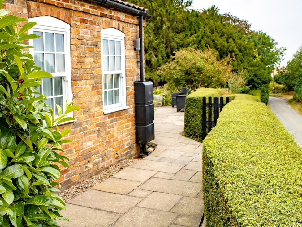 An outdoor space with a brick wall and hedges at Ivy House near Louth