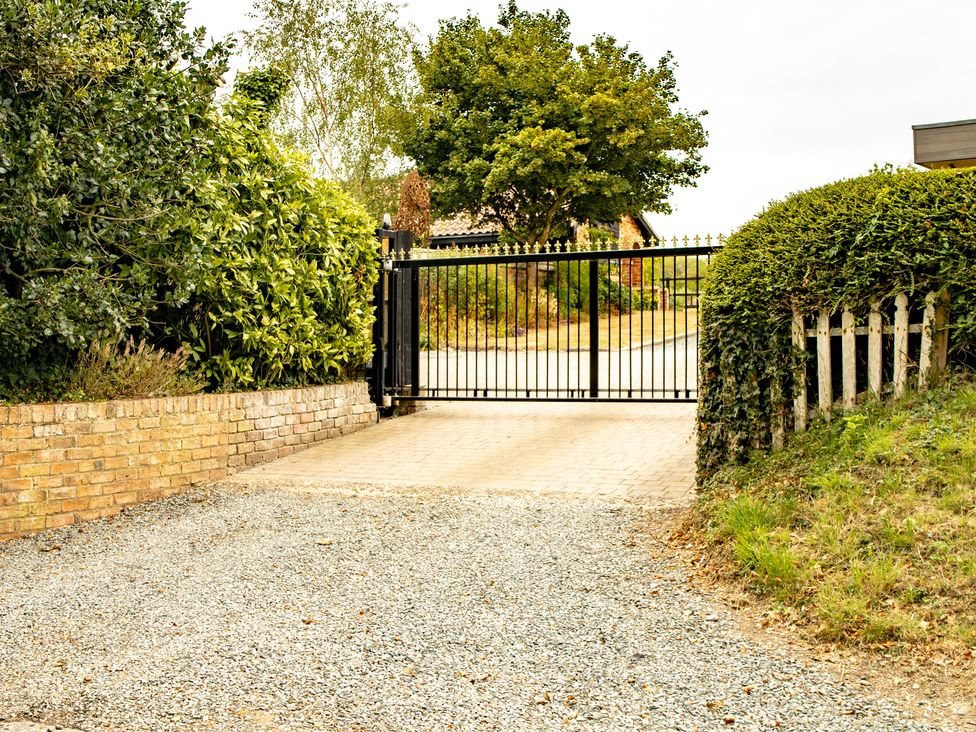 A gravel driveway with a gate and greenery at Ivy House near Louth