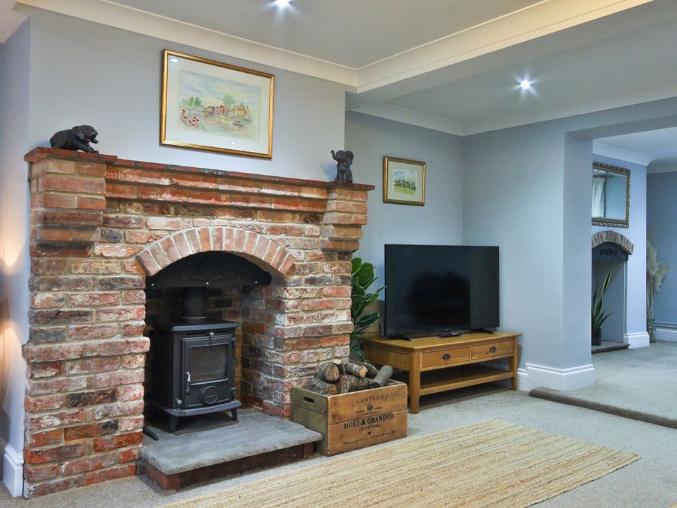 A living room with a fireplace and TV at The Groom's Cottage, at Ivy House near Louth