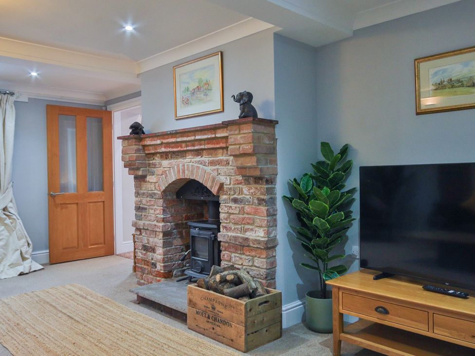 A living room with a brick fireplace and wood stove at The Groom's Cottage, at Ivy House near Louth