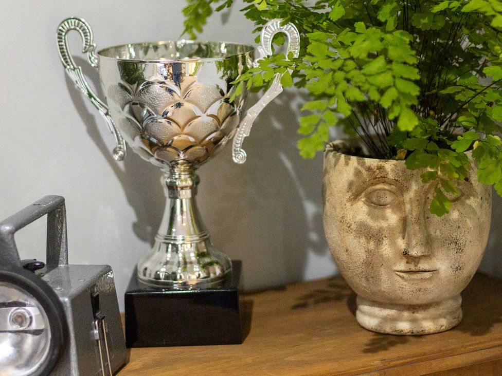 A trophy and a plant in a planter on a shelf at The Groom's Cottage, near Louth