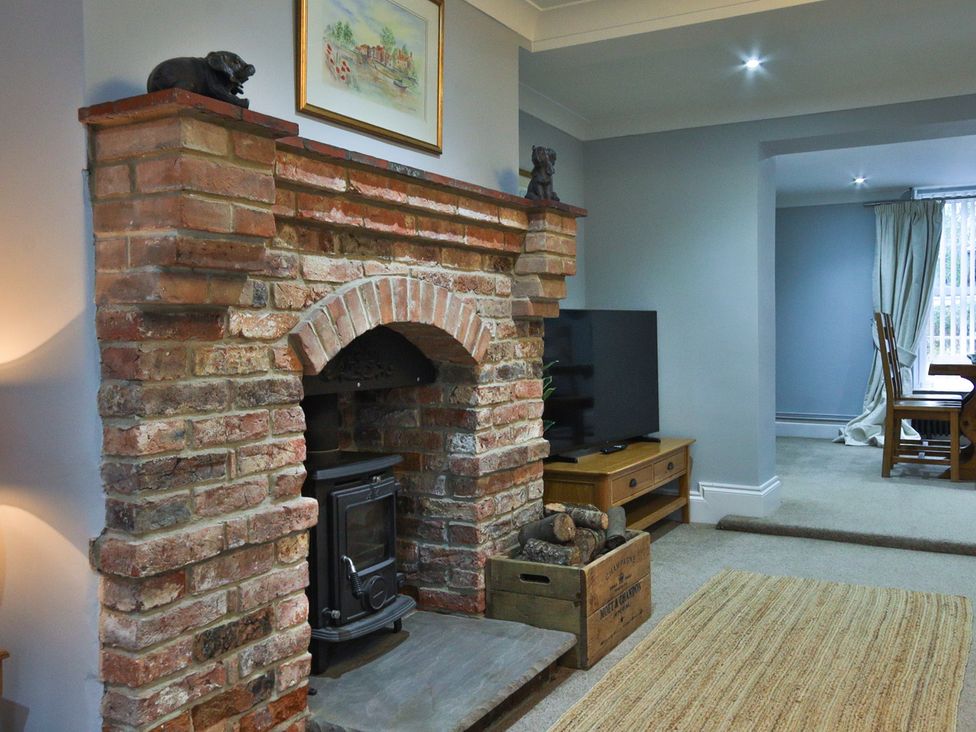 A living room with a fireplace and a television at The Groom's Cottage, at Ivy House near Louth