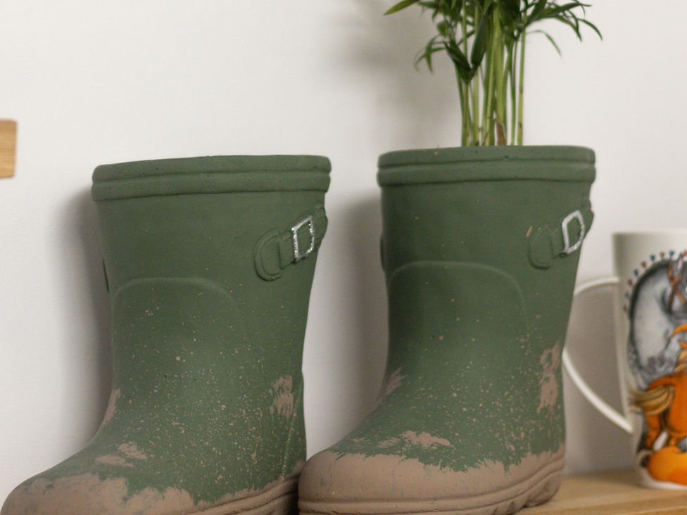 A pair of garden boots with a plant and a mug at The Groom's Cottage, near Louth