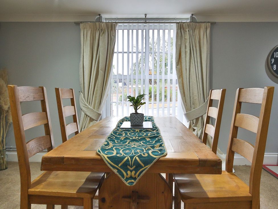 A dining room with a wooden table and chairs at The Groom's Cottage, at Ivy House near Louth