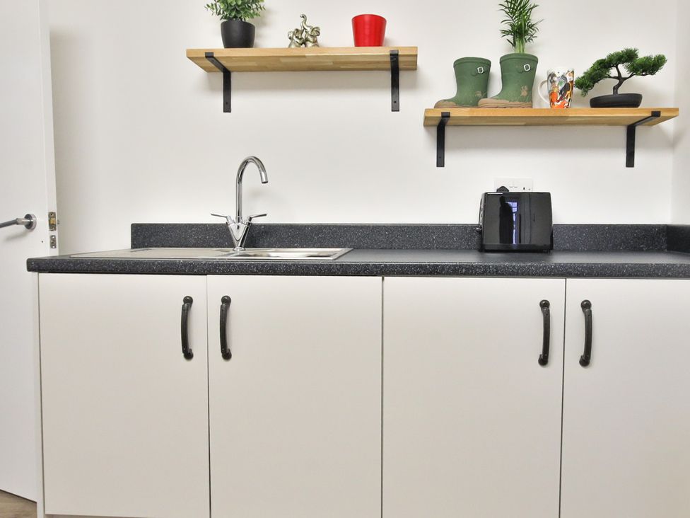 A kitchen with sink and shelves at The Groom's Cottage, at Ivy House near Louth